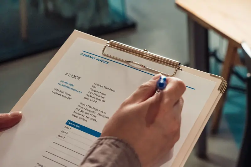 Commercial invoice on a clipboard being checked with a pen