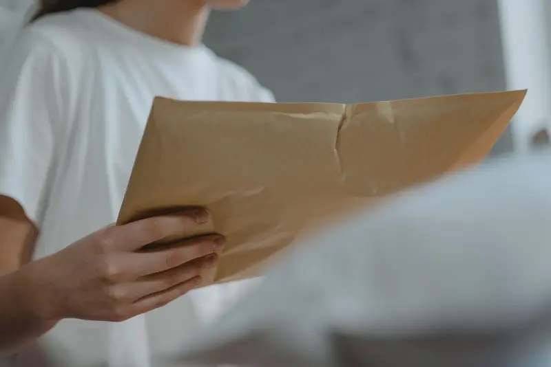 Hand holding a brown courier envelope with documents