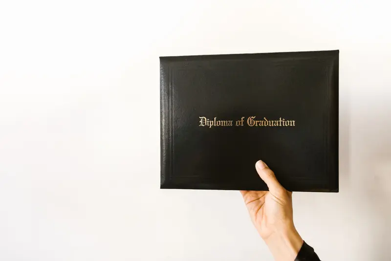Hand holding a university diploma in a dark cover