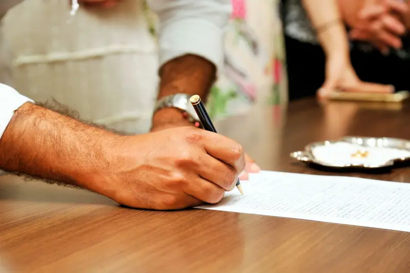 Person signing an official document with a pen at a desk